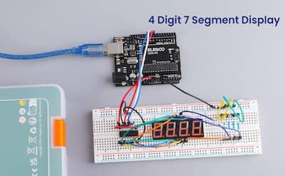 Image of a 4-digit 7-segment display connected to an Arduino Uno board on a breadboard. The display shows the number "8888"